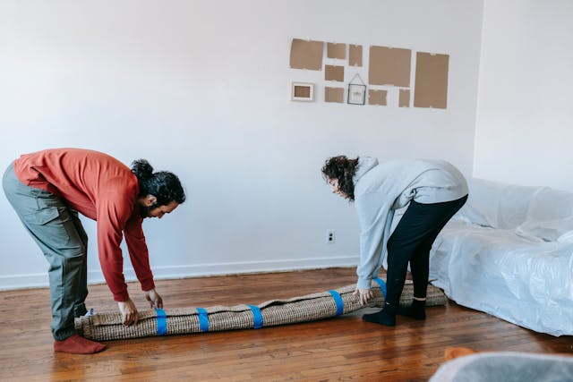 People lifting up a rolled up carpet